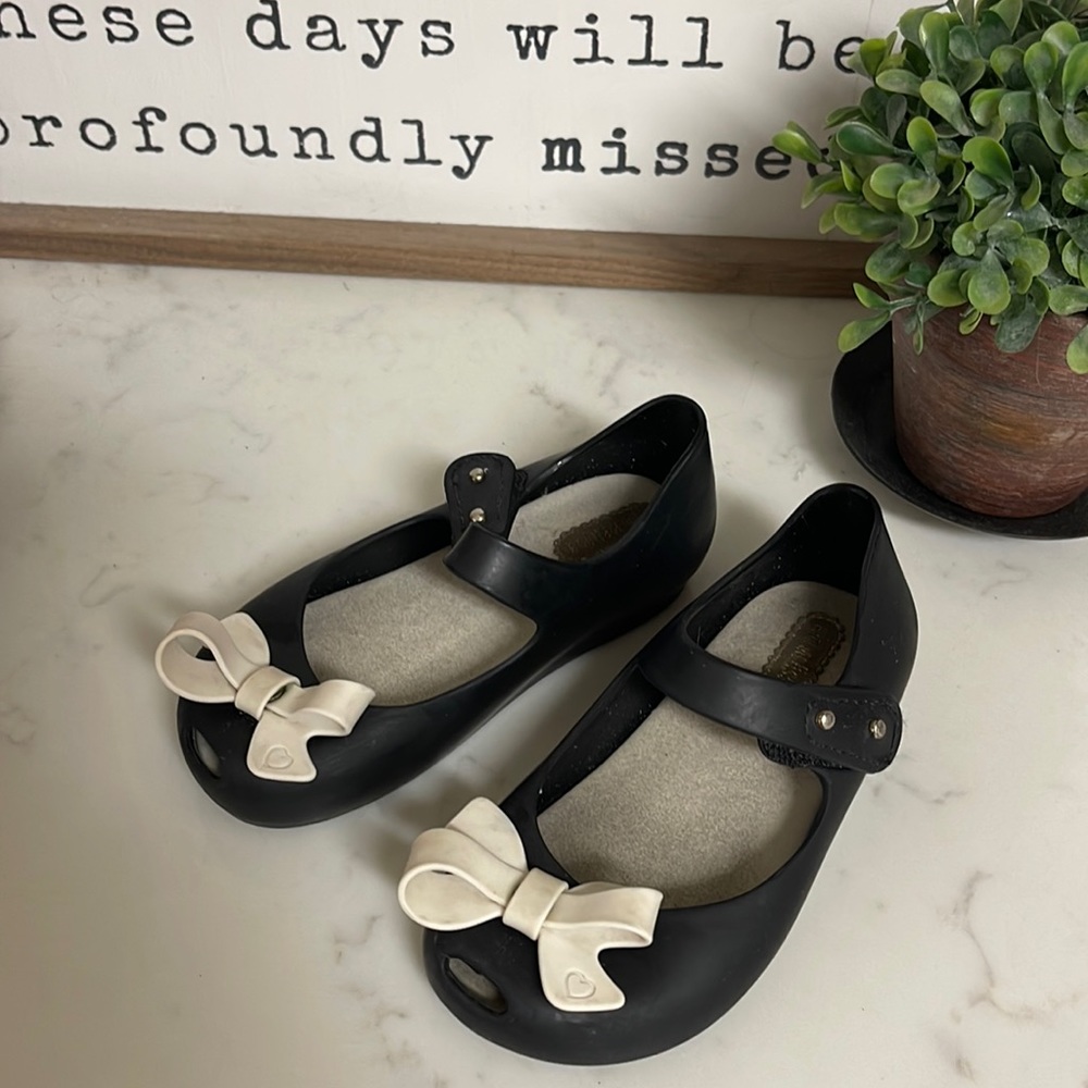 Mini melissa’s black with peep toe and cream colored bow. Maryjanes style.